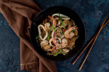 Sebzeli ve deniz mahsullü Asya usulü erişte ve masada yemek çubukları. Yukarıdan görüntüle