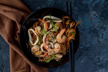Sebzeli ve deniz mahsullü Asya usulü erişte ve masada yemek çubukları. Yukarıdan görüntüle