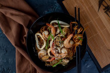 Sebzeli ve deniz mahsullü Asya usulü erişte ve masada yemek çubukları. Yukarıdan görüntüle