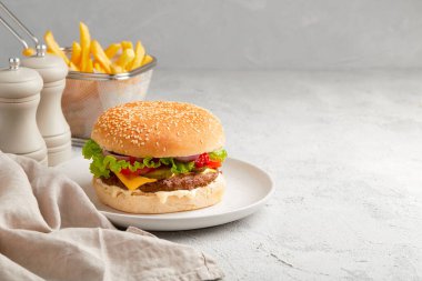 Taze lezzetli hamburger, patates kızartması ve gri arka planda ketçap. Fast food restoran menüsü