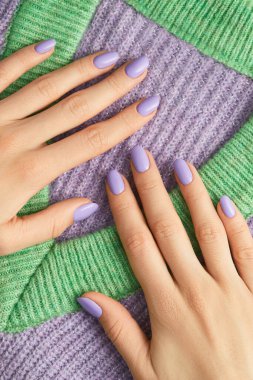 Beautiful womans hands on sweeter with purple fashionable spring nail design. Manicure, pedicure beauty salon concept.