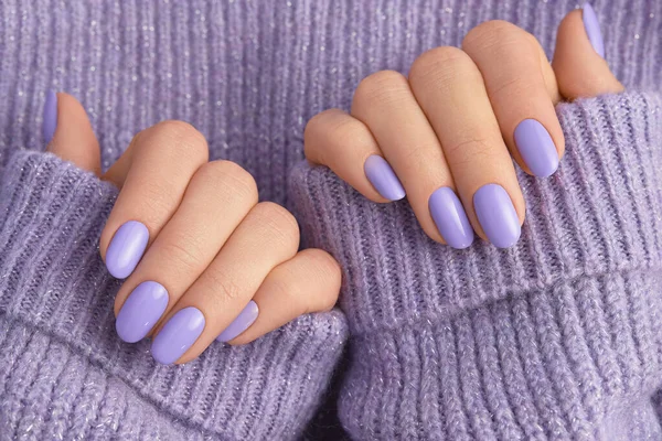 Beautiful womans hands in sweeter with purple fashionable spring nail design. Manicure, pedicure beauty salon concept.