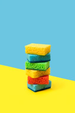 Sarı ve mavi arka planda bulaşık yıkamak için süngerleri olan yaratıcı bir düzen. Temizlik hizmeti kavramı