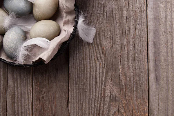 Eggs and feathers on rustic wooden table. Easter celebration concept. Greeting card with space for text.