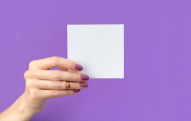 Manikürlü güzel kadın eli mor arka planda kartpostal tutuyor. Güzellik salonu kartviziti şablonu.