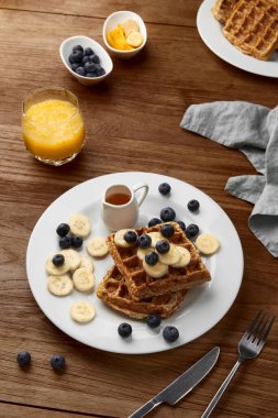 Kırsal ahşap masada muzlu ve yaban mersinli Belçika waffle 'ı. Sağlıklı kahvaltı diyet tarifi