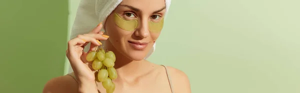 パステルグリーンの背景にグレープシードをベースにしたアイパッチを使用した女性 自然な持続可能なスキンケア 美容治療のコンセプト — ストック写真