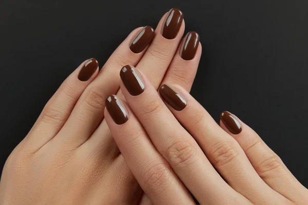 漂亮整洁的女人的手与褐色指甲设计的黑色背景 修指甲 修脚美容院概念 — 图库照片