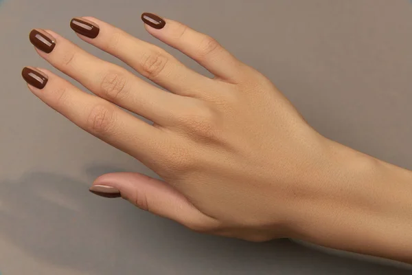 茶色の背景に流行の秋の爪のデザインと美しい手入れの行き届いた女性の手 マニキュア ペディキュア美容室のコンセプト — ストック写真