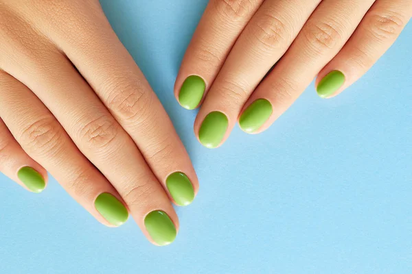 女性的手与绿色的指甲紧密的蓝色背景 美容疗养温泉身体护理 沙龙概念 — 图库照片