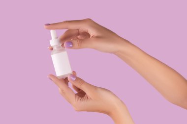 Pastel lavanta arka planında serumu olan kadın el ele tutuşur. Güzellik sağlık cildi konsepti.