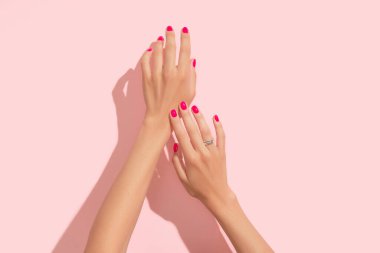 Pembe tırnak desenli kadın elleri. Manikür, pedikür güzellik salonu konsepti. Moda rengi. Derin uzun gölgeler.