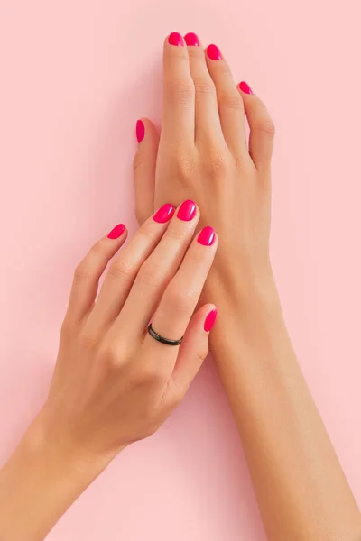 女性的手与时髦的指甲在粉红的粉底上 美容院的概念 平躺在地上 垂直射击 图库照片