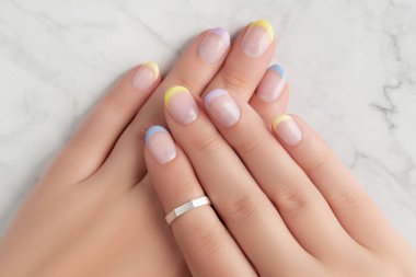 Yazın mermer gri arka planda bahar tırnağı tasarımı olan güzel kadınların elleri. Manikür, pedikür güzellik salonu konsepti