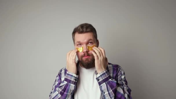 彼の顔に目のパッチを適用する白いTシャツの男の肖像画 セルフケア朝の手順 美容治療のコンセプト — ストック動画