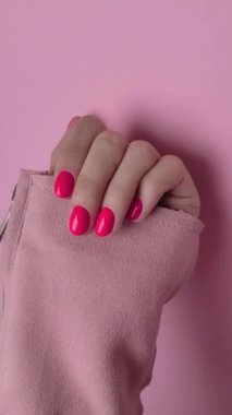 Pastel pembe arka planda moda manikürlü kadın eli. Güzellik salonu konsepti.