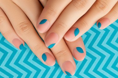 Mavi arka planda yaz manikürü olan kadınların ellerini kapat. Manikür tasarım trendleri. Güzellik tedavi konsepti