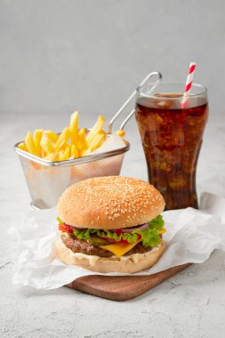 Klasik çizburger, gri arka planda patates kızartması ve soda. Fast food restoranı. Barbekü ızgara menüsü.