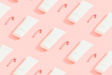 Kozmetik ürünleri ve pembe arka planda şeker kamışı desenleri. Noel indirimi konsepti. Minimalist tarzda yaratıcı kompozisyon