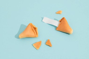 Fortune cookie on a blue background with deep long shadow. Blank paper for prediction words. Background mockup for restaurant social media clipart