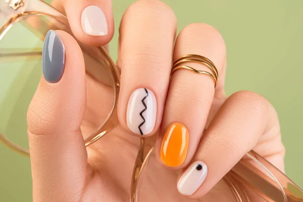 在绿色的背景上用时髦的小修指甲把女人的手绑起来 春夏指甲设计 美容院概念 图库图片
