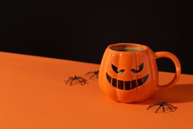 Siyah turuncu arka planda kabak fincanında kapuçino latte kahve. Cadılar Bayramı konsepti. Restoran için menü