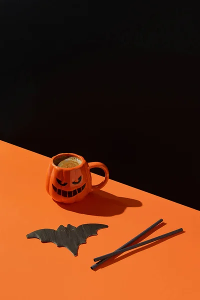 Cappuccino latte coffee in pumpkin cup on black orange background. Halloween celebration concept. Menu for restaurant