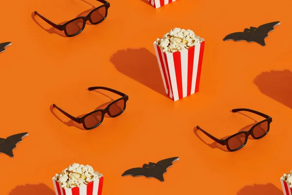 Pattern with striped box with popcorn, bat napkin and 3d glasses on an orange background. Movies, cinema and entertainment. Halloween celebration concept.