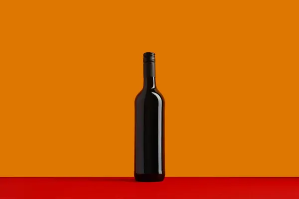 Bottle of red wine on orange and red background. Mock up drink with place for you lable and text. Product packaging brand design.