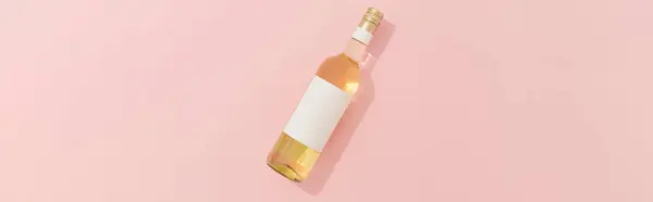 Wine bottle with blank label. White wine on pink background with copy space. Product branding mock up.