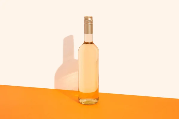 Bottle of white wine on orange background with deep shadows. Mock up drink with place for you lable and text. Product packaging brand design.