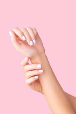 Pembe arka planda beyaz manikürlü kadın elleri. Güzellik tedavi spa vücut bakımı