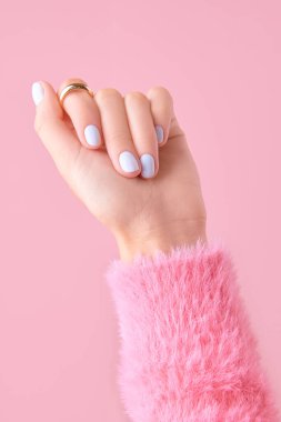 Pembe arka planda beyaz tırnak desenli kadın eli. Manikür, pedikür güzellik salonu konsepti. Tedavi spa vücut bakımı.