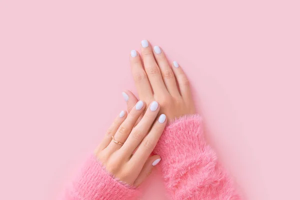 Womans hands with white manicure on pink background. Beauty treatment spa body care