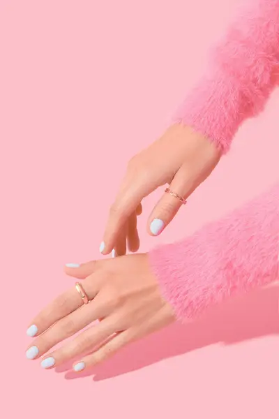 Womans hands with white manicure on pink background. Beauty treatment spa body care