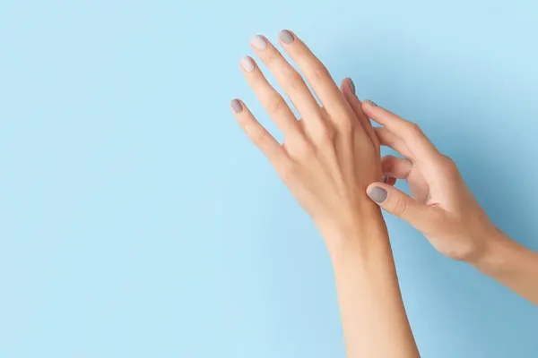 stock image Womans hands with gray nail design on blue background. Manicure, pedicure design trends