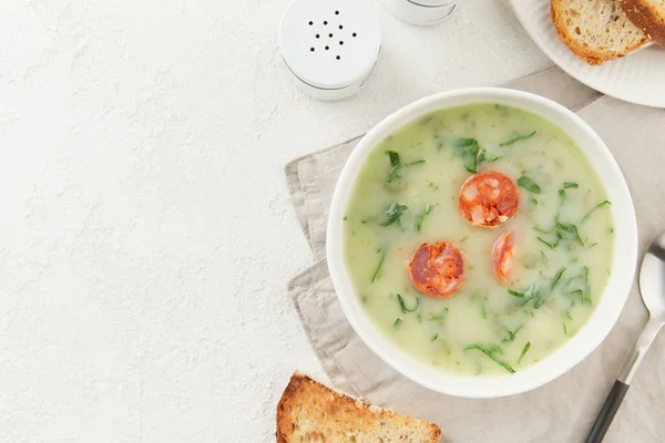 Portuguese style soup Caldo Verde with bread on white table. Traditional Portuguese food. Flat lay copy space
