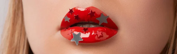 Close up macro womans plump lips with red gloss and silver stars. Beauty fashion portrait personal make up. Beauty salon concept