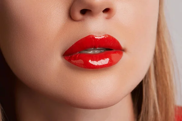 Close up macro female plump lips with red gloss. Beauty fashion portrait personal care and make up. Beauty salon concept
