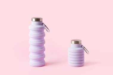 Collapsible reusable lilac water bottle on pink background. Plastic-free packaging. Sustainability, eco-friendly lifestyle clipart