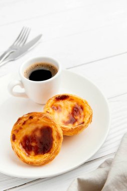 Geleneksel Portekiz yumurtalı tart tatlısı Pasteis Pastel de nata ya da Pasteis de Belem, beyaz arkaplanlı kahve. Yerel hamur işi kahvaltı konsepti