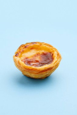 Geleneksel Portekiz yumurtalı tart tatlısı Pasteis Pastel de nata veya Pasteis de Belem mavi arka planda. Yerel hamur işi kafeteryası kavramı