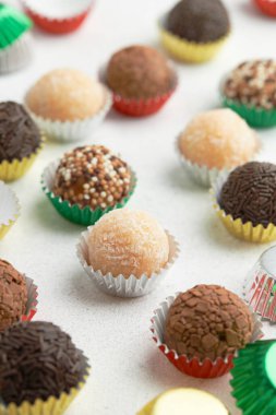 Tipik Brezilya tatlı tugayı, yoğunlaştırılmış süte dayanıyor. Beyaz bir masa üzerinde renkli kağıt kalıplarda çeşitli tatlar.