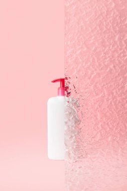 Pastel pembe arka planda bir şişe samimi hijyen jeli. Vücut bakımı güzellik tedavi konsepti. 