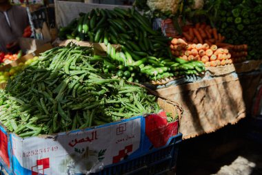 HURGHADA, EGYPT - 20 Şubat 2022: otantik Mısır pazarının tezgahında yeşil bezelyeler, salatalıklar, havuçlar. Sokak pazarında taze sebzeler. Doğal ekolojik gıda.