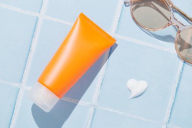 Mavi arka planda güneş kremi. Yazlık bakım ürünleri plaj aksesuarları. Vücut bakımı güzellik tedavisi