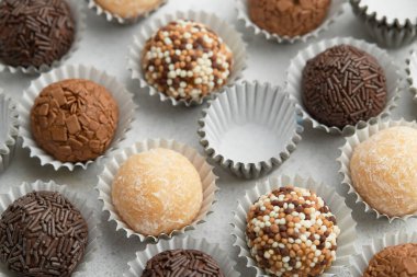 Tipik Brezilya tatlı tugayı, yoğunlaştırılmış süte dayanıyor. Beyaz bir masada çeşitli aromalı şekerlemelerin üst görüntüsü. Desen