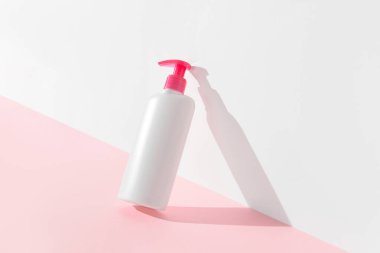 Pastel pembe ve beyaz arka planda bir şişe samimi hijyen jeli. Vücut bakımı güzellik tedavi konsepti. 