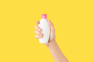 Sarı arka planda beyaz şişeyi tutan kadınlar. Kişisel bakım güzellik tedavi kavramı.
