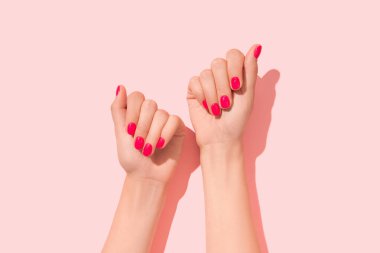 Pembe tırnak desenli kadın elleri. Manikür, pedikür güzellik salonu konsepti. Derin uzun gölgeler. Moda rengi